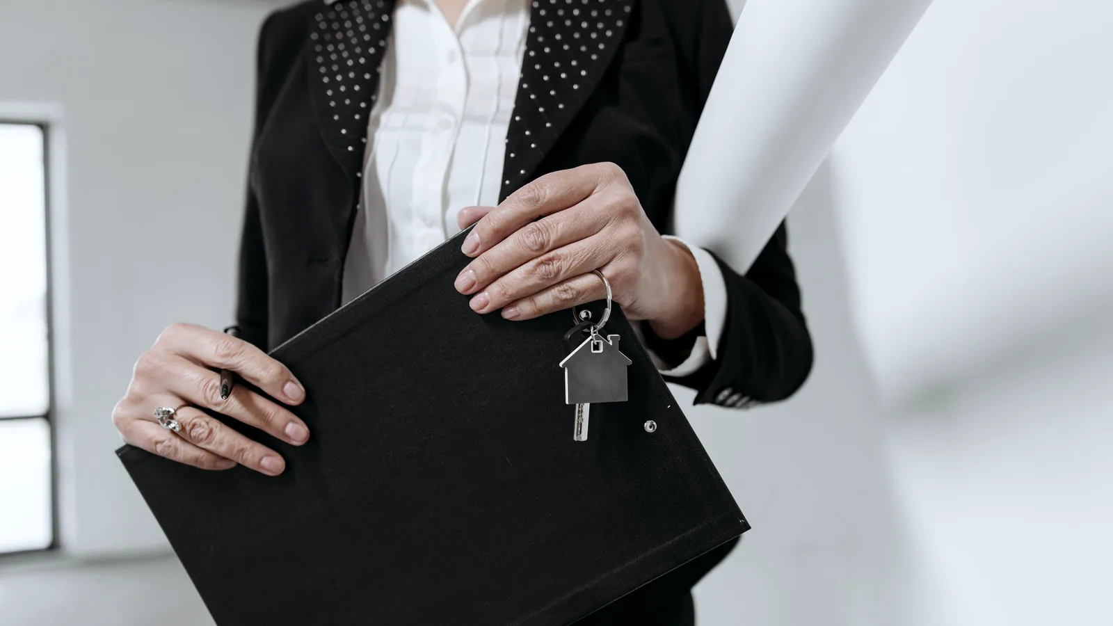 Manos que sostienen una carpeta y las llaves de una casa