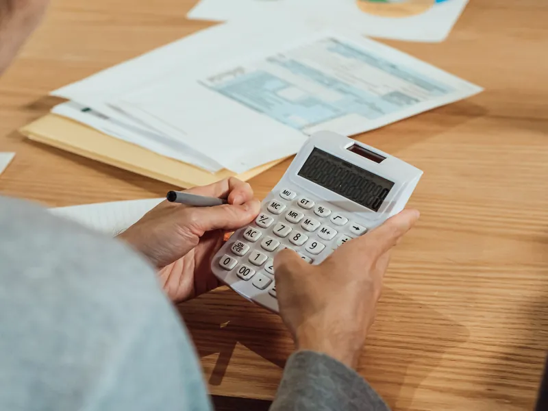 Manos usan una calculadora junto a unos formularios