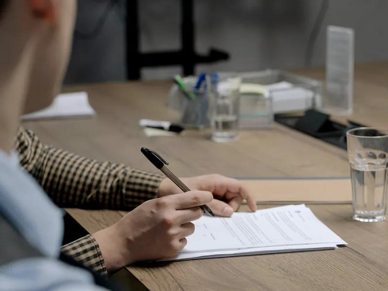 Mano firma un documento sobre una mesa de reuniones