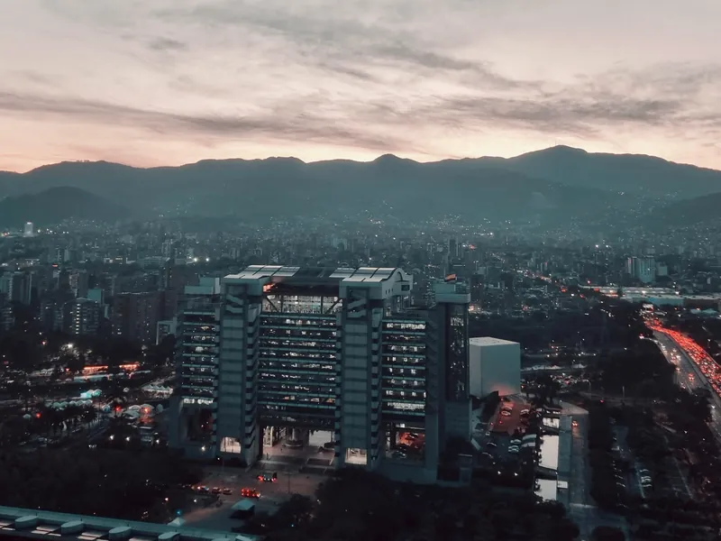 Edificio institucional del centro administrativo de Medellín al anochecer, con las montañas al fondo