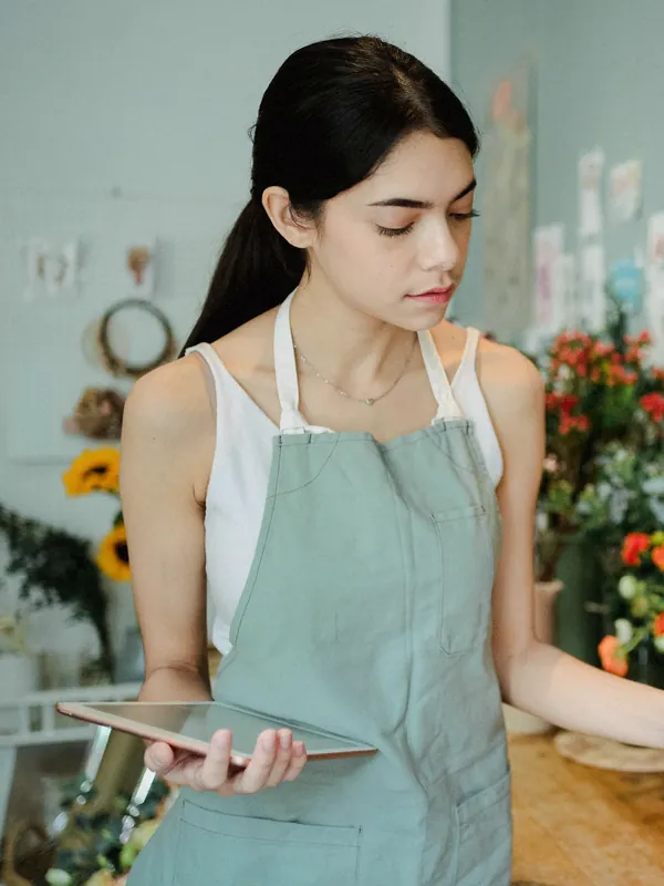 Dueña de una floristería revisa pedidos en una tableta