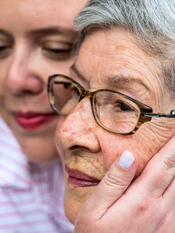 Una mujer abraza con ternura a una señora mayor